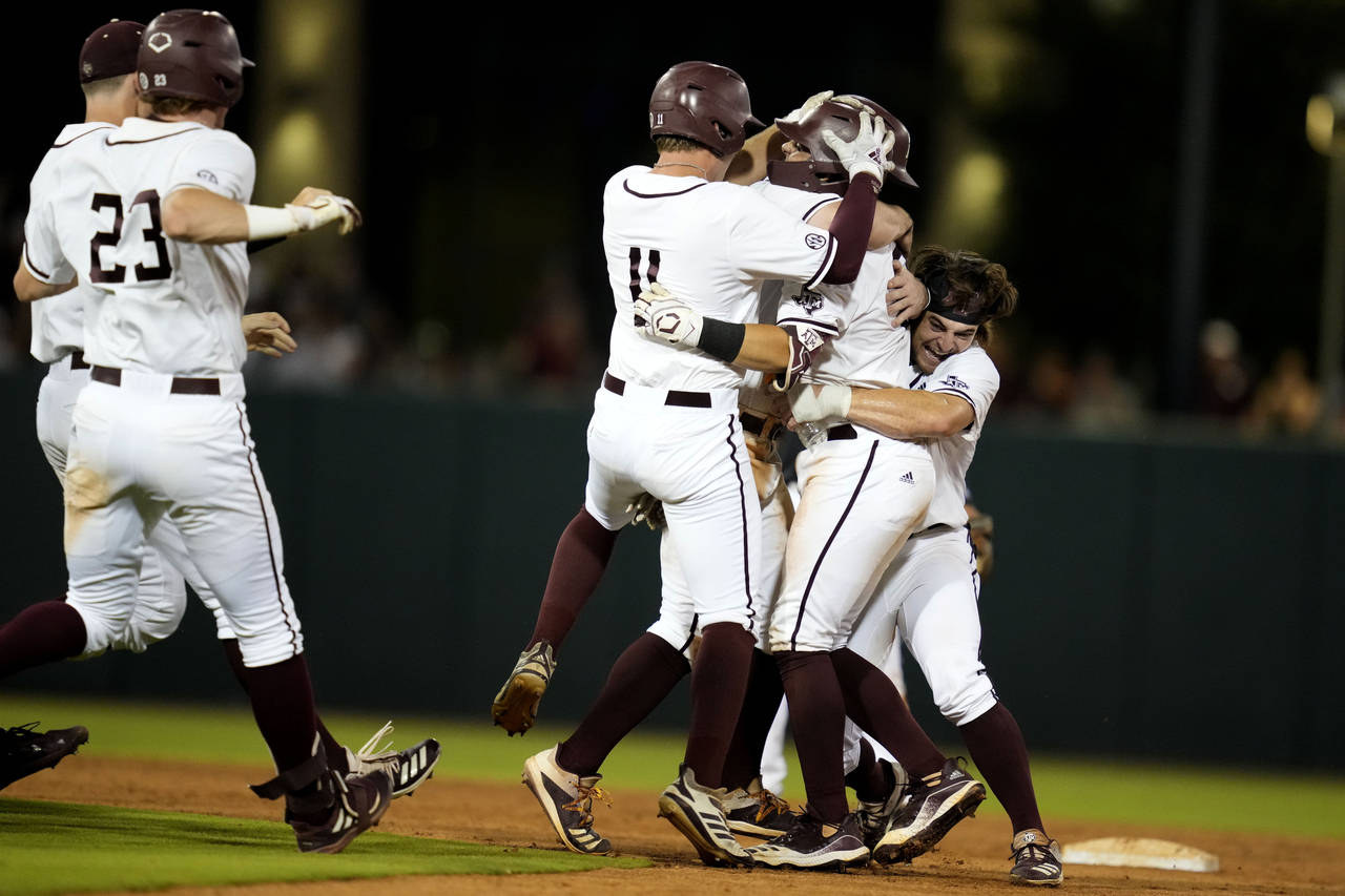 Texas A&M's Troy Claunch, center, is swarmed by teammates after driving in the winning run with a s...