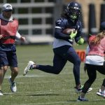 Amanda Ruller, right, who is currently working as an assistant running backs coach for the NFL football Seattle Seahawks through the league's Bill Walsh Diversity Fellowship program, runs a drill with DeeJay Dallas, center, during NFL football practice May 31, 2022 in Renton, Wash. Ruller's job is scheduled to run through the Seahawks' second preseason game in August. (AP Photo/Ted S. Warren)