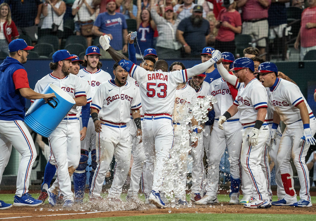 Texas Rangers' Adolis Garcia (53) is congratulated by teammates at home plate after hitting a walko...