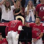 Los Angeles Angels' Mike Trout, right, puts a cowboy hat on Shohei Ohtani after Ohtani hit a solo home run during the third inning of a baseball game against the Seattle Mariners Saturday, June 25, 2022, in Anaheim, Calif. (AP Photo/Mark J. Terrill)