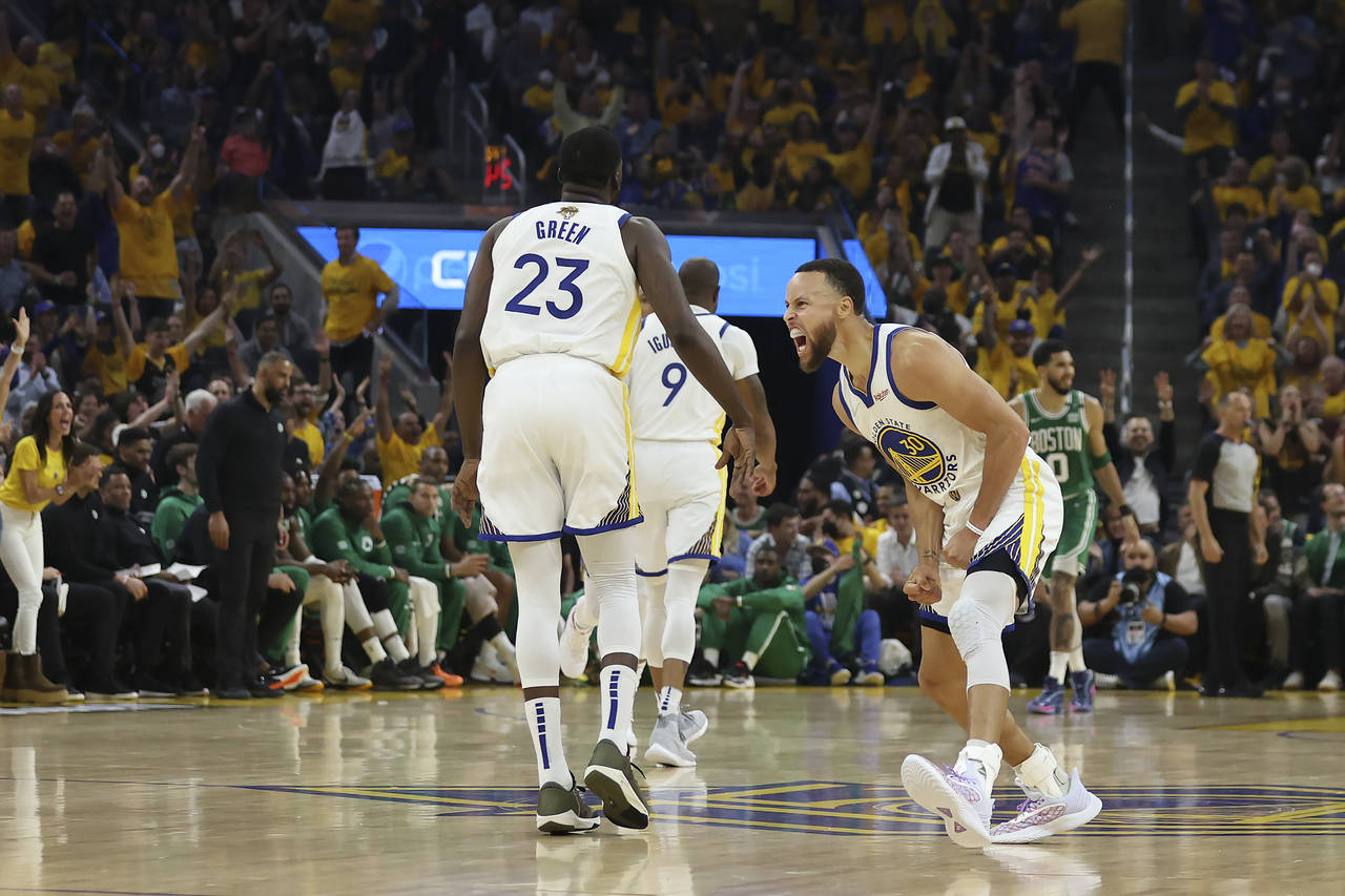 Golden State Warriors guard Stephen Curry, right, celebrates with forward Draymond Green (23) durin...