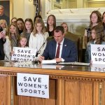 
              FILE - Oklahoma Gov. Kevin Stitt signs a bill in Oklahoma City on Wednesday, March 30, 2022, that prevents transgender girls and women from competing on female sports teams. Stitt signed the bill flanked by more than a dozen young female athletes, including his eighth-grade daughter Piper. (AP Photo/Sean Murphy, File)
            
