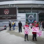
              Young fans hold signs and make thumbs-down gestures outside B.C. Place stadium after the Canadian national men's soccer team's friendly match against Panama was canceled due to a labor dispute, in Vancouver, British Columbia, Sunday, June 5, 2022. (Darryl Dyck/The Canadian Press via AP)
            