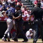 
              CORRECTS THAT WINKER WAS HIT BY A PITCH, NOT A CLOSE PITCH AS ORIGINALLY SENT -  Seattle Mariners' Jesse Winker, left, pushes third base umpire Adrian Johnson out of the way as he heads toward the Los Angeles Angels' dugout after getting hit by a pitch as home plate umpire John Bacon, second from right, holds catcher Max Stassi back during the second inning of a baseball game Sunday, June 26, 2022, in Anaheim, Calif. (AP Photo/Mark J. Terrill)
            