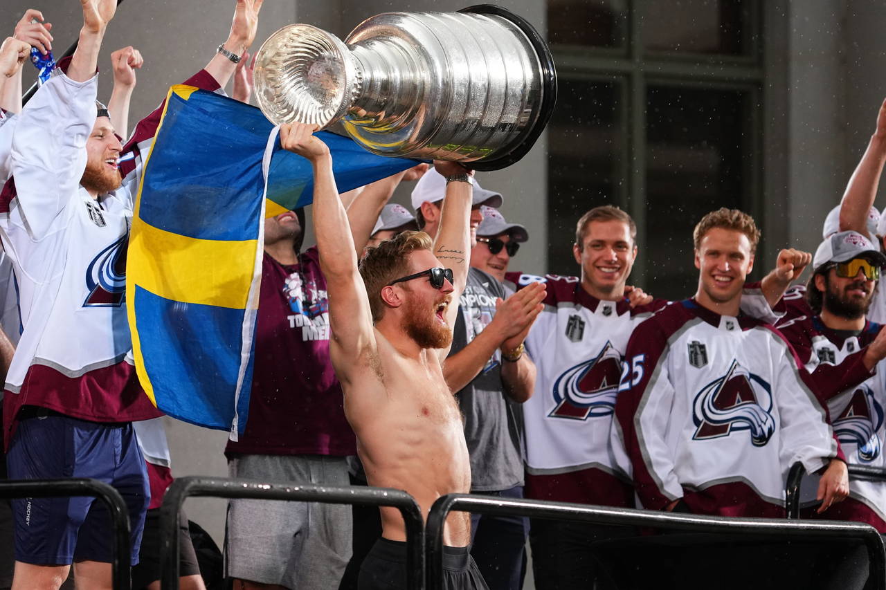 Colorado Avalanche left wing Gabriel Landeskog hoists the Stanley Cup and a flag of Sweden at a ral...