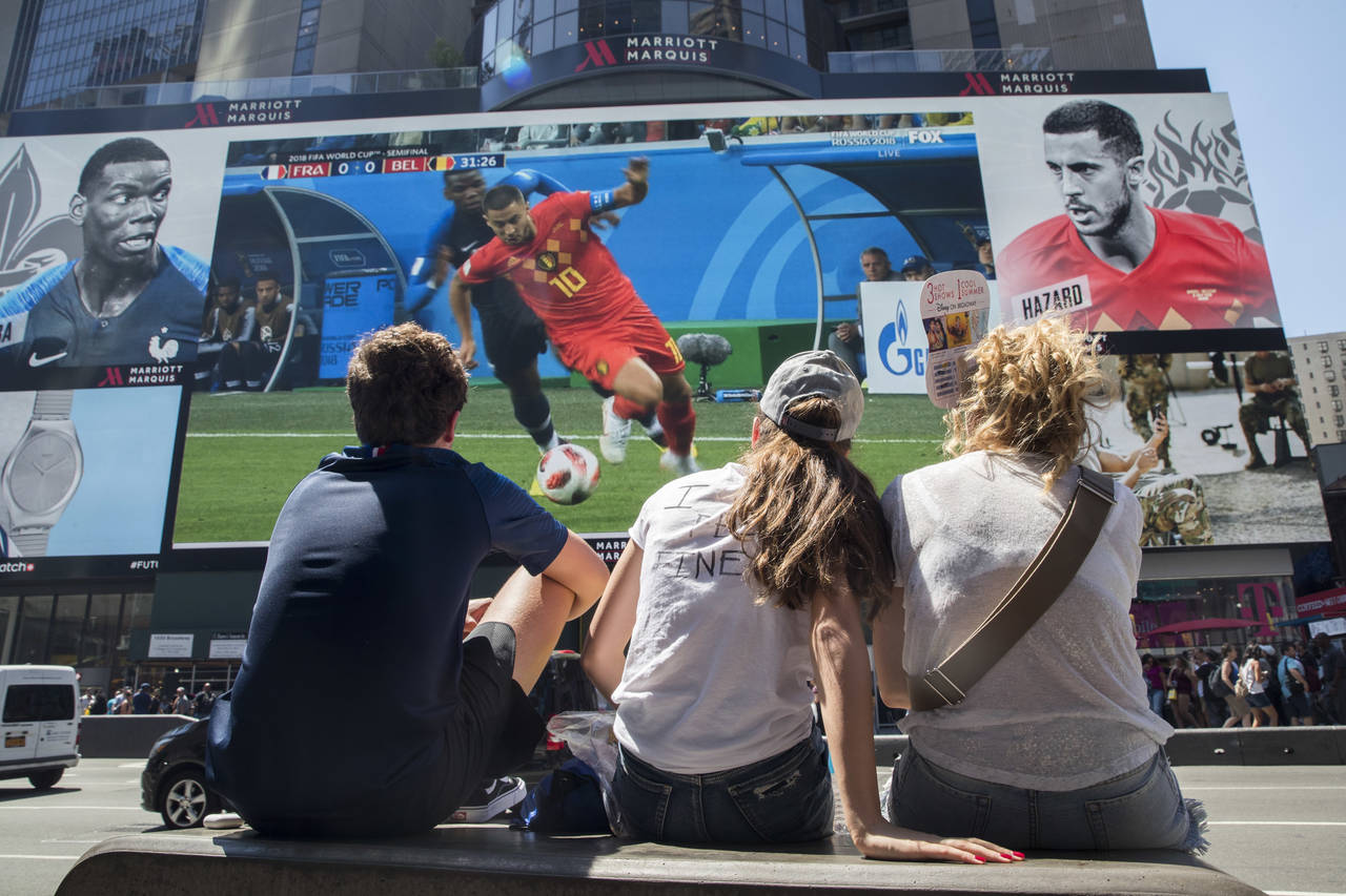FILE - French soccer fans watch France play Belgium in a World Cup semifinal soccer game on a gigan...