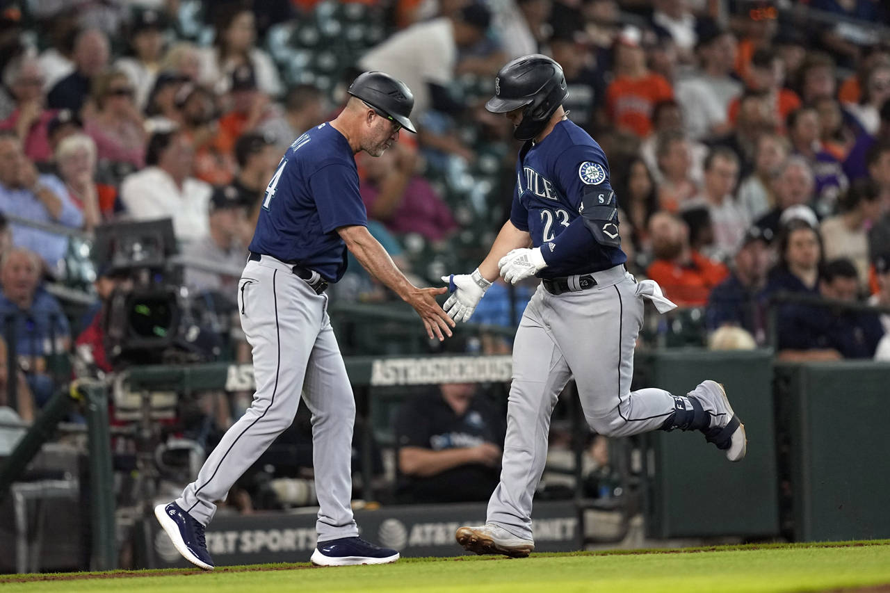 Seattle Mariners' Ty France (23) celebrates with third base coach Manny Acta after hitting a home r...