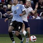 
              USA forward Paul Arriola, right, kicks the ball past Uruguay defender Mathias Olivera (16) during the second half of an international friendly soccer match Sunday, June 5, 2022, in Kansas City, Kan. The match ended in a 0-0 tie. (AP Photo/Charlie Riedel)
            