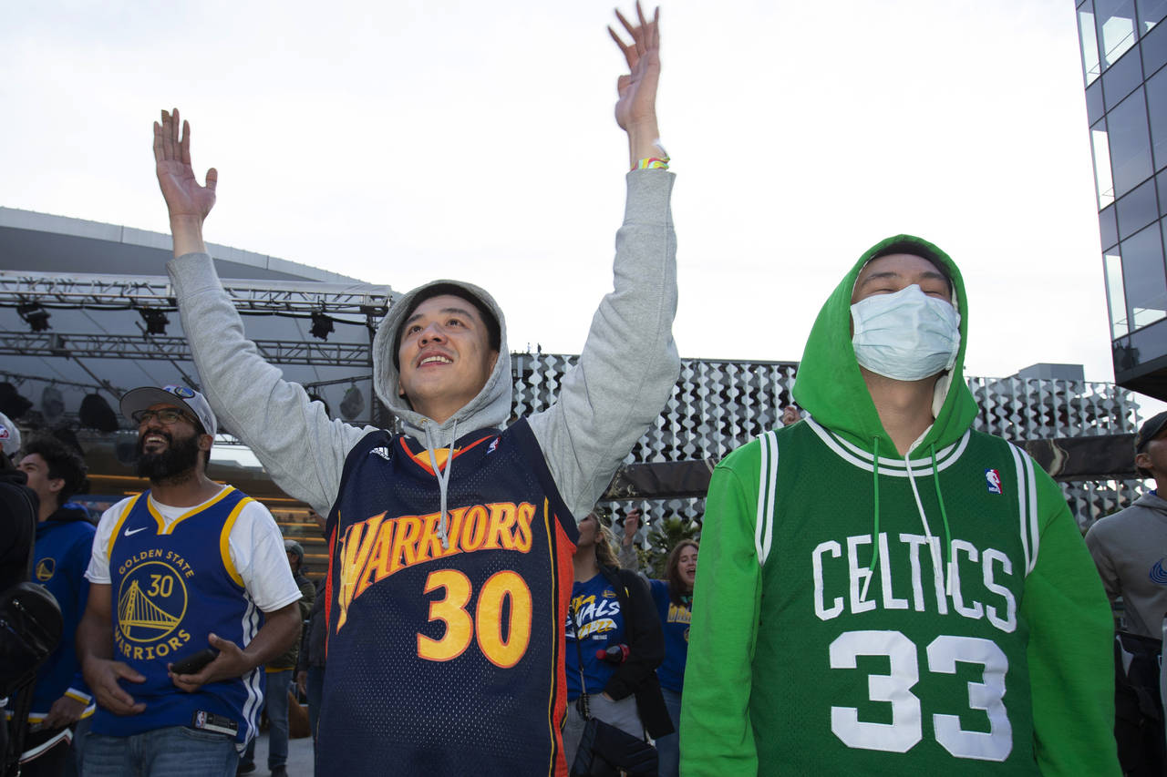Golden State Warriors fan Andrew Pai, left, of San Jose, Calif., cheers on his team while standing ...