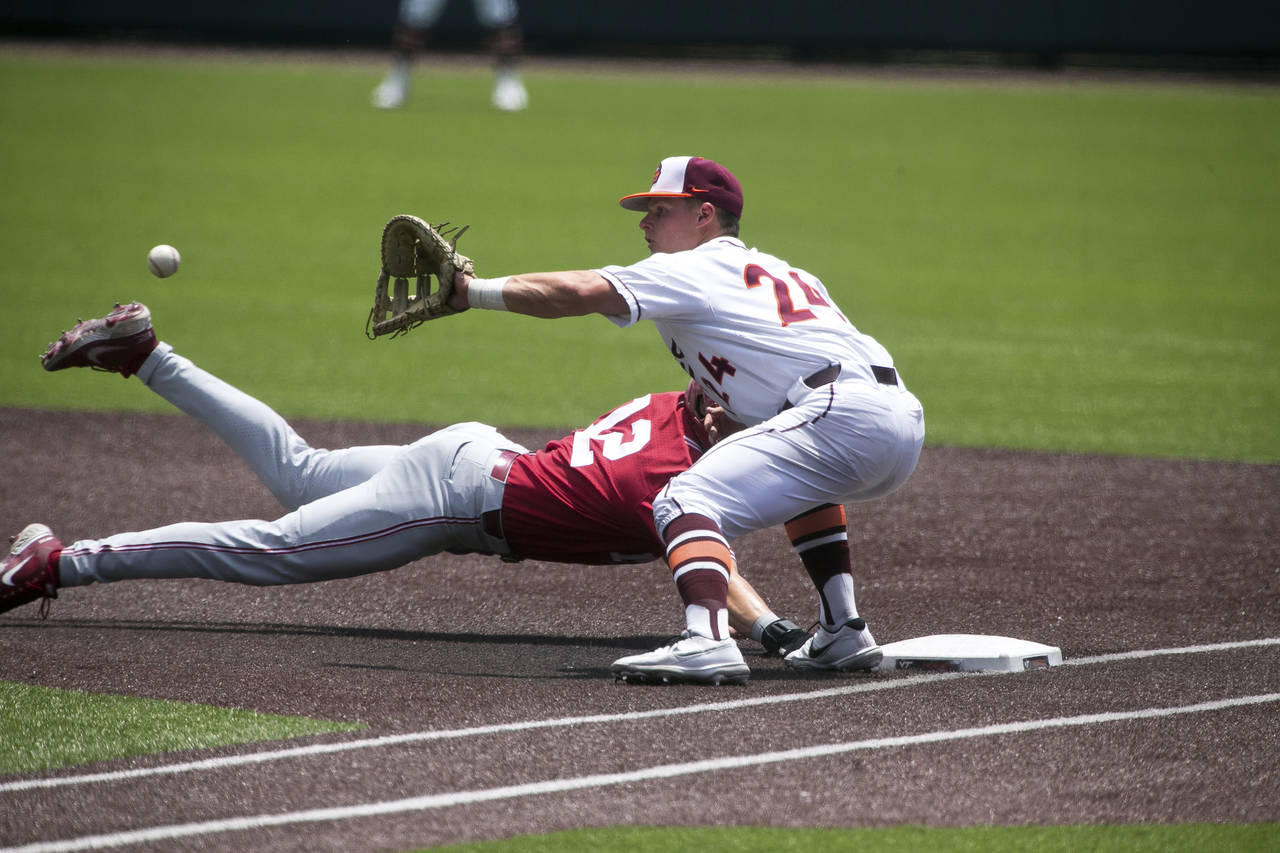 Oklahoma's Brett Squires (12) beats the tag at first base from Virginia Tech's Nick Biddison (24) i...