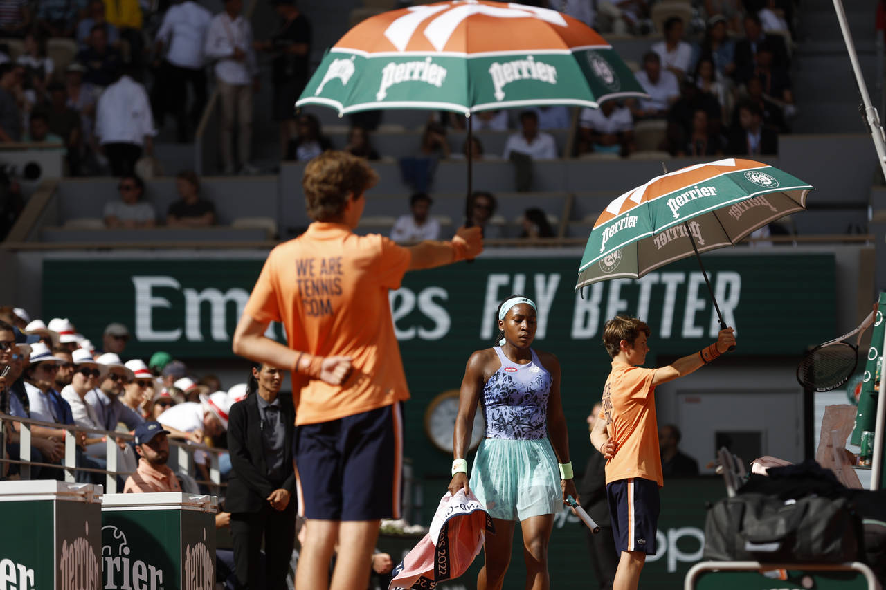 Ball boys carry umbrellas as Coco Gauff of the U.S.walks back to her bench while she plays Italy's ...