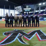 
              A South Florida Urban Search and Rescue Team stands for a moment of silence to remember the victims of the Surfside building collapse, before a baseball game between the Miami Marlins and the New York Mets, Friday, June 24, 2022, in Miami. (AP Photo/Lynne Sladky)
            