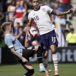 
              Uruguay defender Guillermo Varela (4) and USA forward Christian Pulisic (10) battle for the ball during the first half of an international friendly soccer match Sunday, June 5, 2022, in Kansas City, Kan. (AP Photo/Charlie Riedel)
            