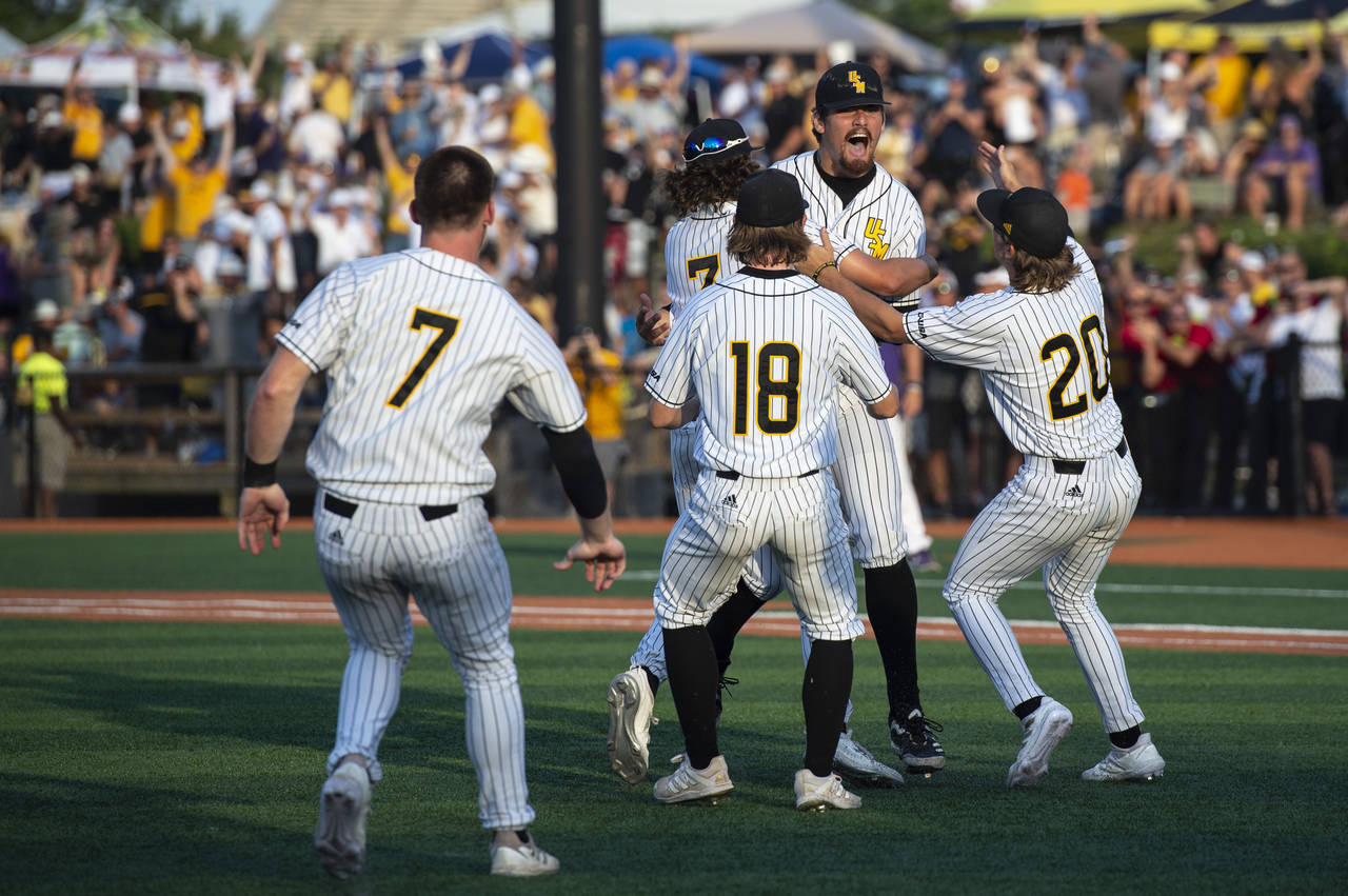 Southern Miss pitcher Tyler Stuart is embraced by his teammates as Southern Miss defeated LSU after...