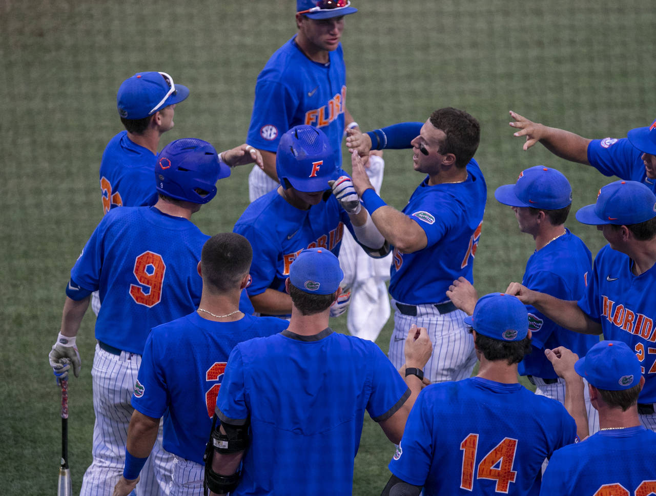 Florida's Jud Fabian, second from top, celebrates with teammates after his home run against Oklahom...