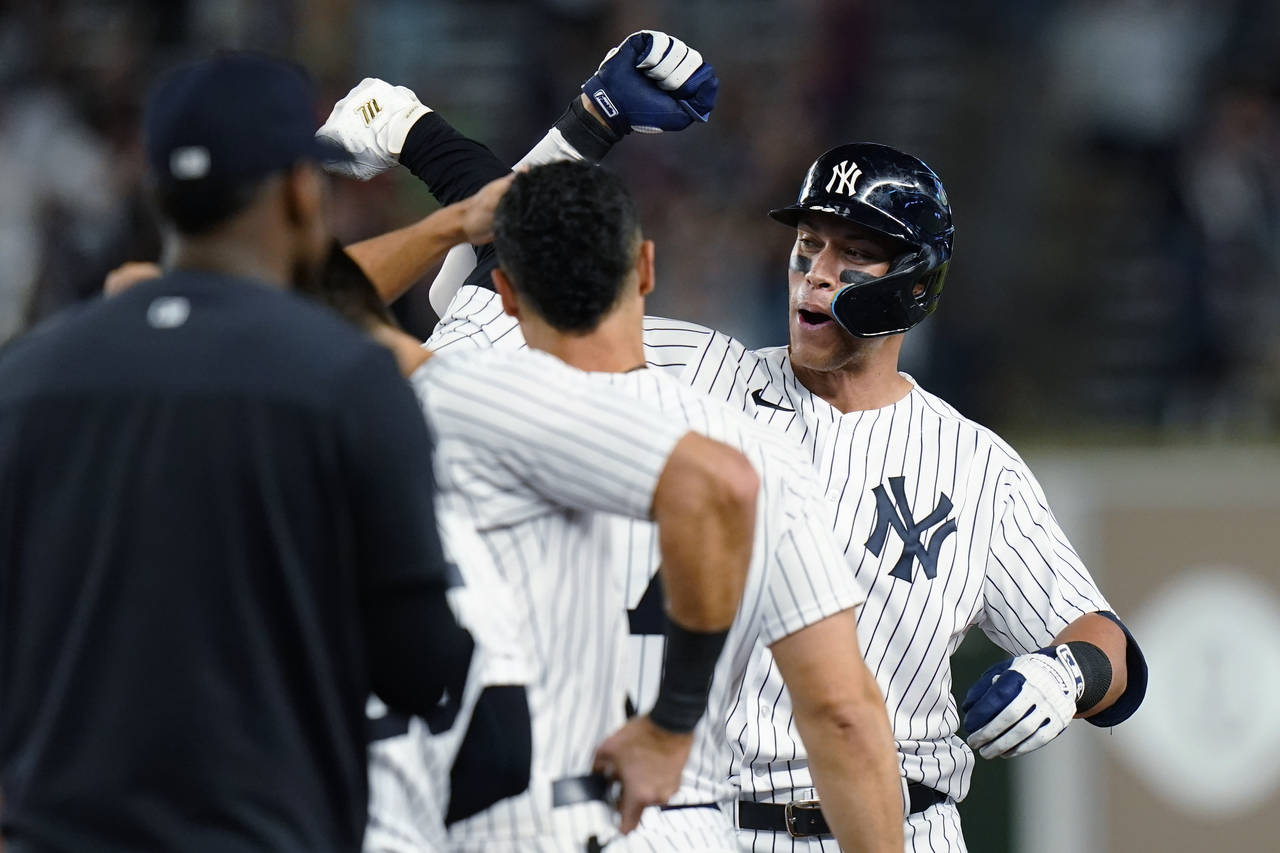 New York Yankees' Aaron Judge celebrates with teammates after hitting a single to drive in the winn...