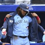 
              Toronto Blue Jays' Vladimir Guerrero Jr (27) gets the home run jacket put onto him by Santiago Espinal, hidden, after hitting a solo home run against the Minnesota Twins during the third inning of a baseball game Friday, June 3, 2022, in Toronto. (Jon Blacker/The Canadian Press via AP)
            