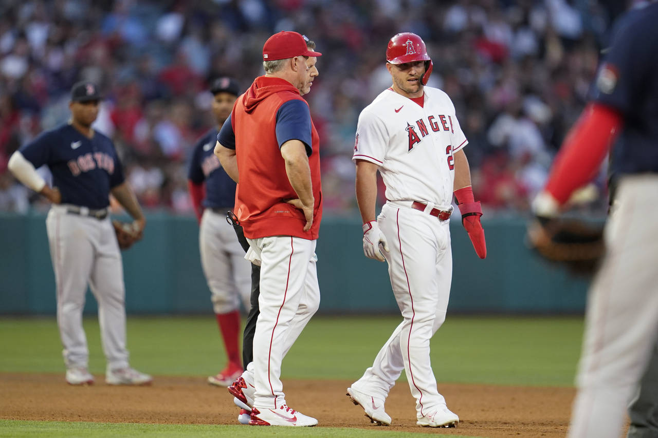 Los Angeles Angels' Mike Trout, center right, is checked out during the third inning of a baseball ...