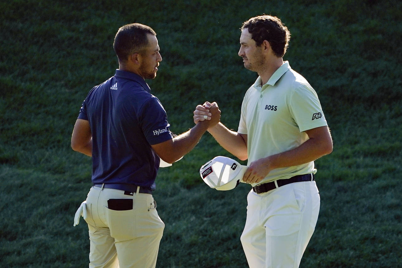 Xander Schauffele, left, and Patrick Cantlay shake hands after finishing the third round of the Tra...