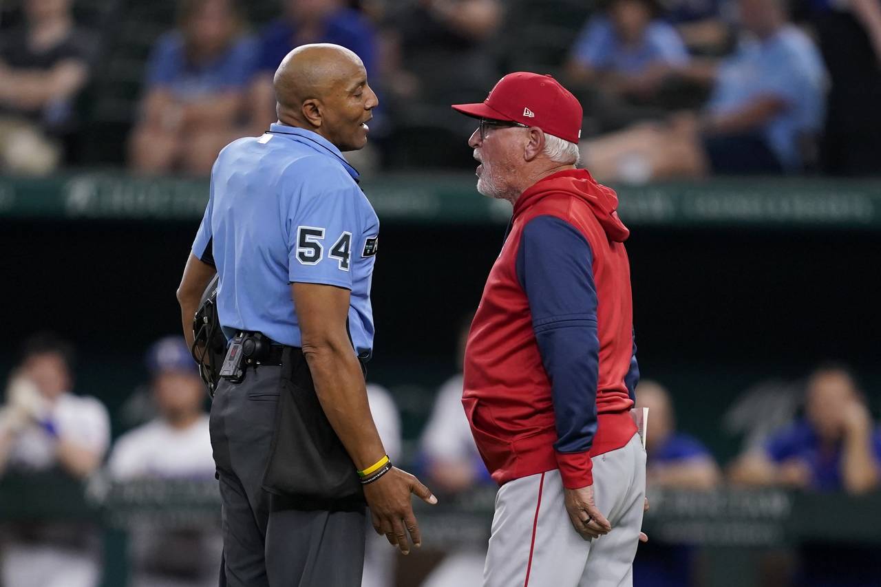 Umpire CB Bucknor talks with Los Angeles Angels manager Joe Maddon, right, after ejecting Maddon du...
