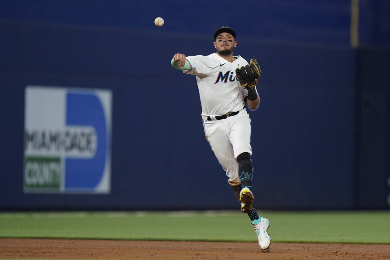 Miami Marlins shortstop Miguel Rojas throws to first to put out Colorado Rockies' Yonathan Daza dur...