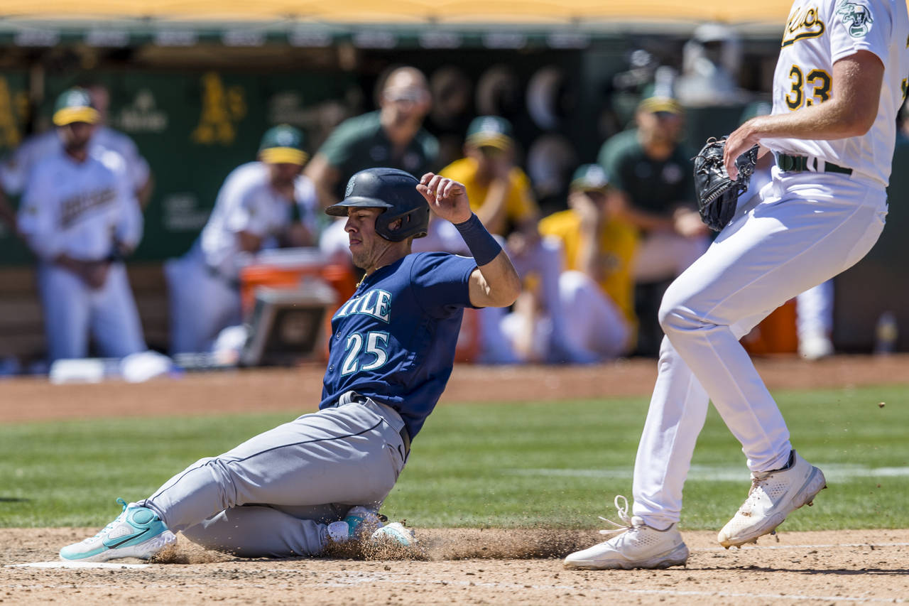 Seattle Mariners' Dylan Moore (25) scores on a wild pitch by Oakland Athletics' A.J. Puk (33) durin...