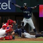 ARLINGTON, TEXAS - JULY 14: Sam Haggerty #0 of the Seattle Mariners slides home on an inside the park home run as Julio Rodriguez #44 reacts in the fourth inning against the Texas Rangers at Globe Life Field on July 14, 2022 in Arlington, Texas. (Photo by Richard Rodriguez/Getty Images)