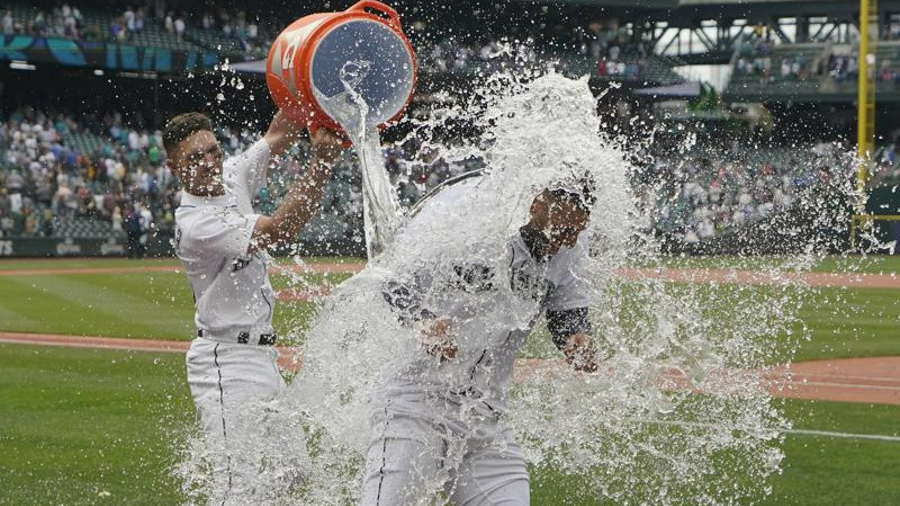 Seattle Mariners' Abraham Toro, right, has water dumped onto him by Adam Frazier, left, after Toro ...