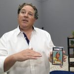 
              Chris Ivy, Heritage Auctions Director of Sports Auctions, holds and talks about a Mickey Mantle baseball card at in Dallas, Thursday, July 21, 2022. The mint-condition Mantle card is expected to sell well into the millions when bidding ends at the end of the month. (AP Photo/LM Otero)
            