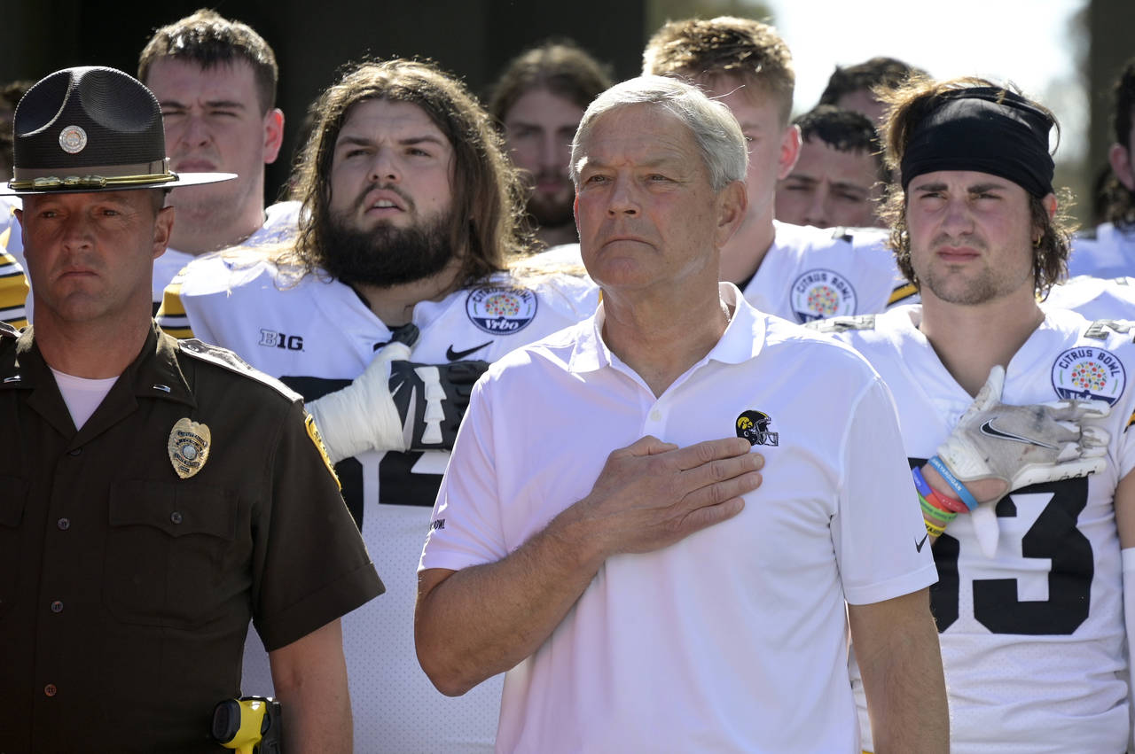 FILE - Iowa head coach Kirk Ferentz, front right, stands for the national anthem before the Citrus ...