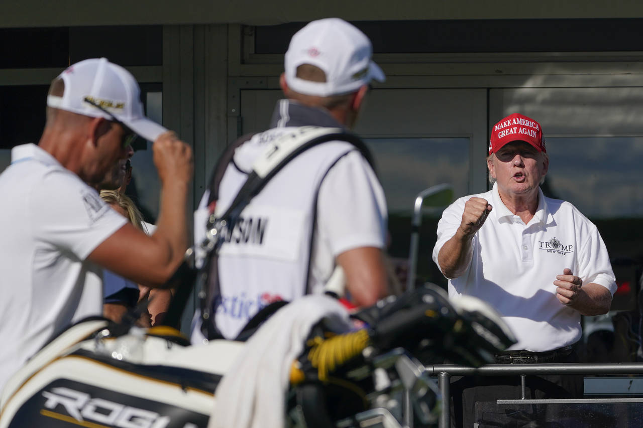 Former President Donald Trump gestures toward Henrik Stenson, who was leaving the 16th tee during t...
