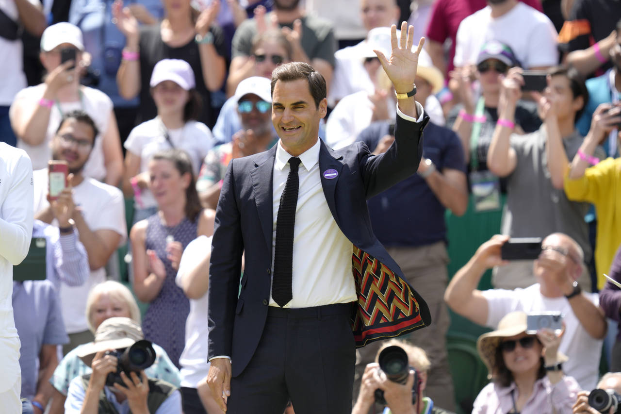Switzerland's Roger Federer waves during a 100 years of Centre Court celebration on day seven of th...
