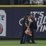 
              A fan who ran onto the field during the seventh inning is taken away by King County Sheriff's Deputies during a baseball game between the Seattle Mariners and the Oakland Athletics, Sunday, July 3, 2022, in Seattle. (AP Photo/Ted S. Warren)
            