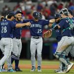 
              Seattle Mariners' Eugenio Suarez (28), Dylan Moore (25), Cal Raleigh, right, and others celebrate their 3-2 win against the Texas Rangers in a baseball game, Saturday, July 16, 2022, in Arlington, Texas. (AP Photo/Tony Gutierrez)
            