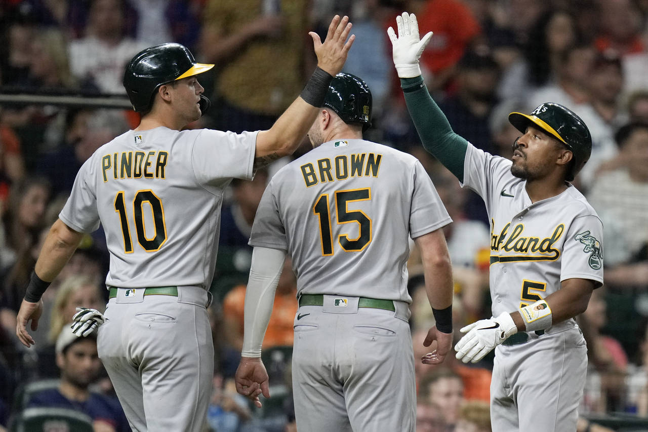 Oakland Athletics' Chad Pinder (10) celebrates with Tony Kemp, right, after scoring during the seve...