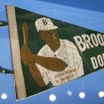 
              FILE - A banner with a picture of Brooklyn Dodgers baseball player Jackie Robinson is displayed at the exhibit "In the Dugout with Jackie Robinson: An Intimate Portrait of a Baseball Legend" at the Museum of City of New York in New York, Jan. 29, 2019. Already at the forefront on the 75th anniversary of breaking baseball’s color barrier, Jackie Robinson’s life, legacy and impact is honored as part of the 2022 baseball All-Star Game in Los Angeles. (AP Photo/Seth Wenig, File)
            