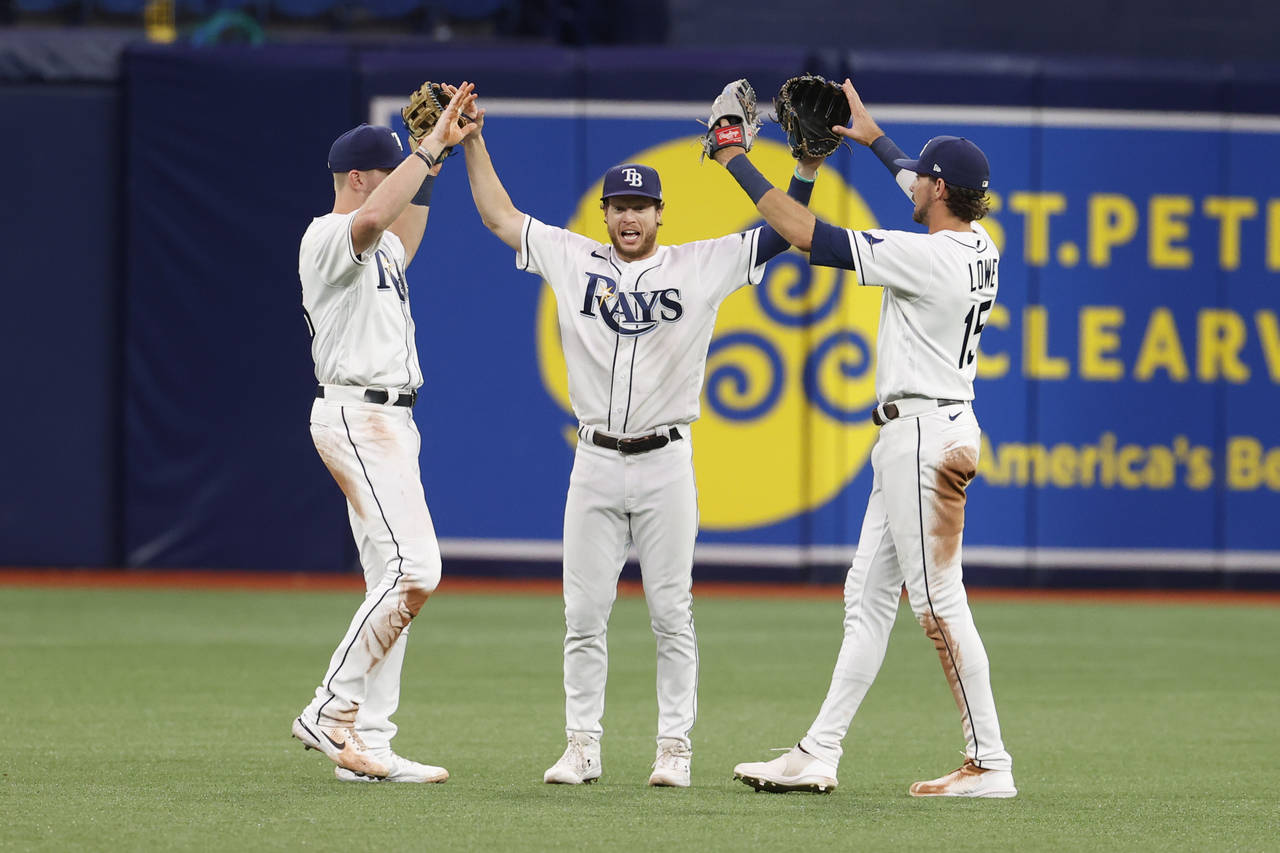 Tampa Bay Rays right fielder Brett Phillips, center, celebrates with teammates Luke Raley, left, an...