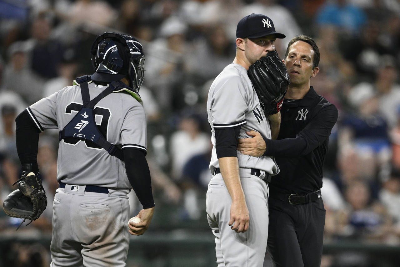 New York Yankees relief pitcher Michael King, center, is tended to by a trainer during the eighth i...