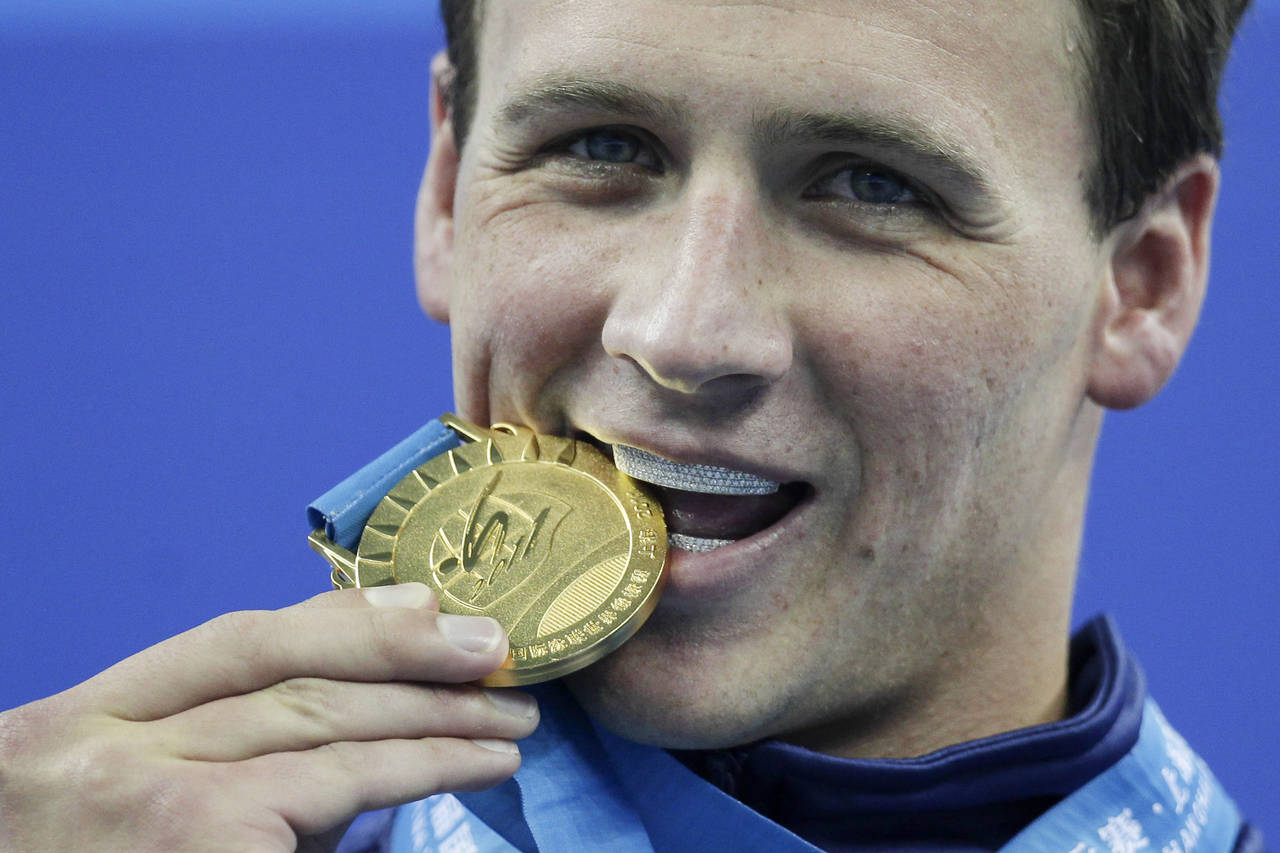 FILE - Ryan Lochte, of the United States, bites his gold medal for the men's 200 meters freestyle a...