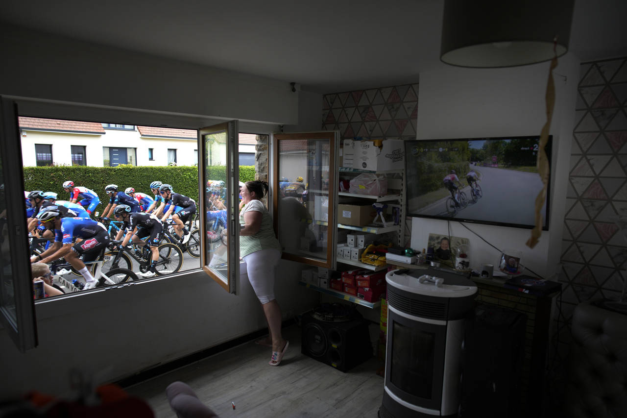 FILE - A woman cheers the riders, as she stands at her window, during the fourth stage of the Tour ...