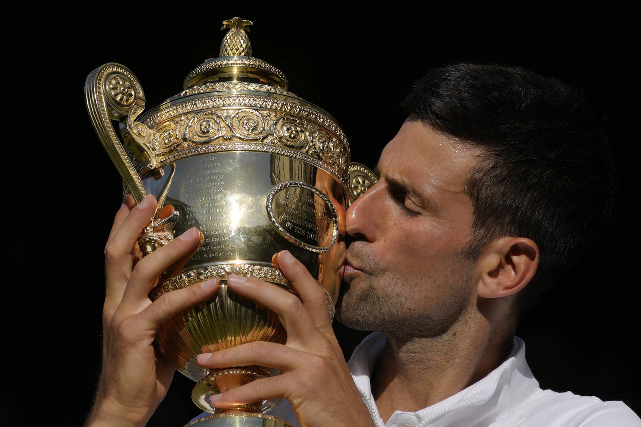 Serbia's Novak Djokovic kisses the trophy as he celebrates after beating Australia's Nick Kyrgios t...