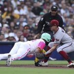 
              San Diego Padres Nomar Mazara, left, dives back to third base as Arizona Diamondbacks' Josh Rojas prepares to apply the tag in the second inning of a baseball game Friday, July 15, 2022, in San Diego. Mazara was out on the play. (AP Photo/Derrick Tuskan)
            