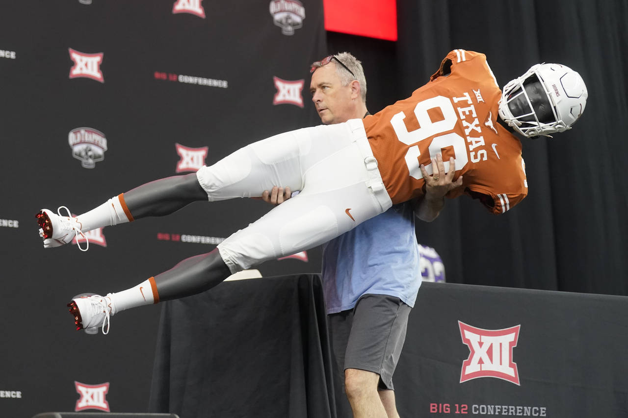 Brad Clements carries off a mannequin wearing a Texas football uniform as he dismantles the stage a...