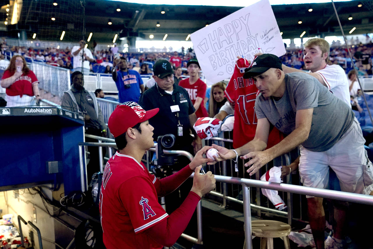 A fan holds a happy birthday sign as Los Angeles Angels' Shohei Ohtani signs autographs before the ...