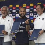 
              Flanked by Miguel Mejia Baron, UNAM's vice president of sports, left, and Leopoldo Silva, Pumas club president, right, Brazilian Dani Alves holds his contract during a press conference where he was presented as a new member of the Pumas UNAM soccer club, in Mexico City, Saturday, July 23, 2022.  (AP Photo/Marco Ugarte)
            