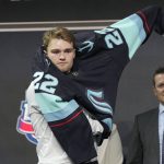 
              Shane Wright pulls on a Seattle Kraken jersey after being selected with the fourth pick in the NHL hockey draft in Montreal on Thursday, July 7, 2022. (Ryan Remiorz/The Canadian Press via AP)
            