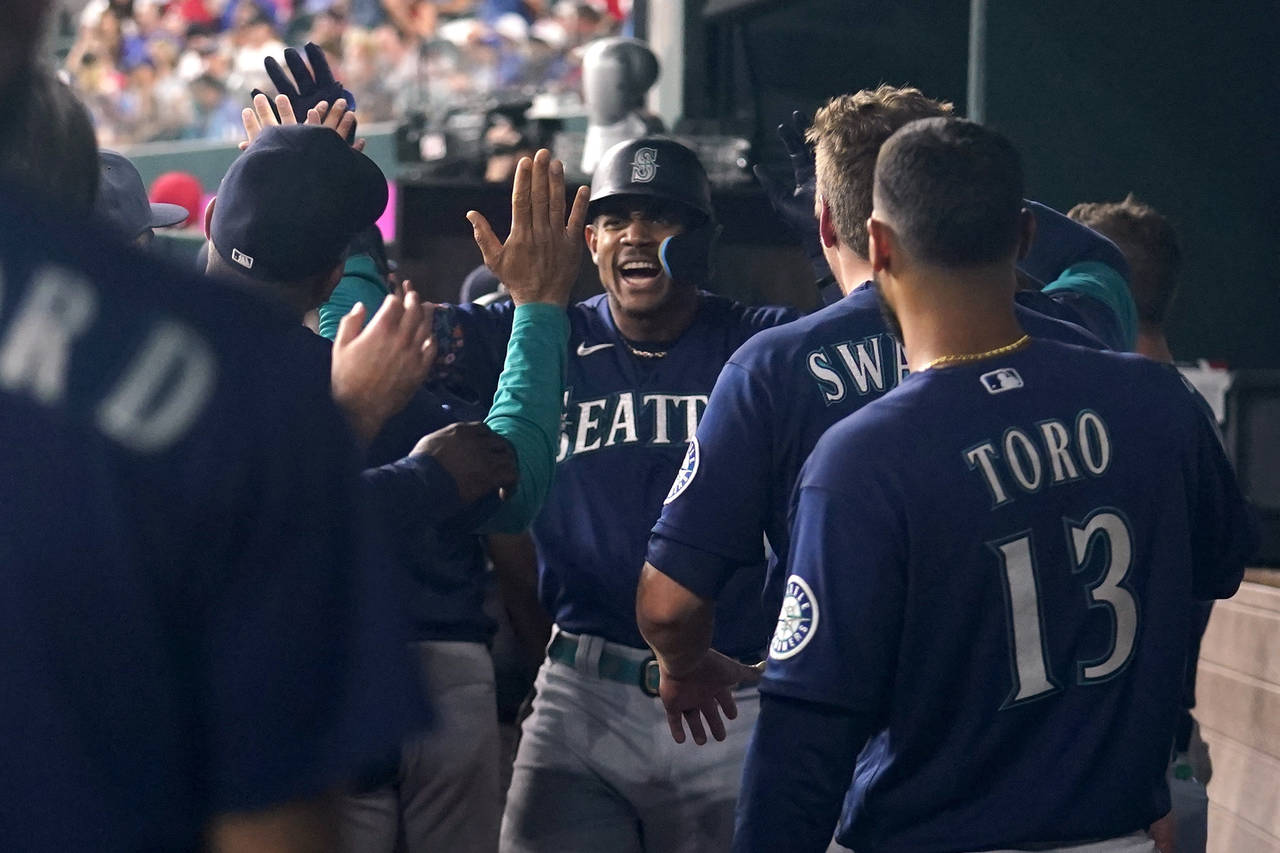 Seattle Mariners' Julio Rodriguez, center, celebrates in the dugout after Rodriguez hit a grand sla...