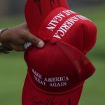 
              A man carries caps just signed by former President Donald Trump during the first round of the Bedminster Invitational LIV Golf tournament in Bedminster, N.J., Friday, July 29, 2022. (AP Photo/Seth Wenig)
            