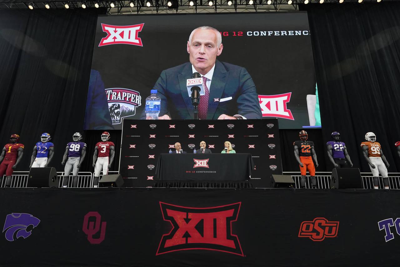 Incoming Big 12 Commissioner Brett Yormark, center, speaks with outgoing Commissioner Bob Bowlsby, ...