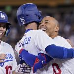 
              Los Angeles Dodgers' Mookie Betts, right, celebrates with Cody Bellinger, center, as Will Smith stands by after Betts drove in the winning run and Bellinger scored it during the ninth inning of a baseball game against the Colorado Rockies Wednesday, July 6, 2022, in Los Angeles. (AP Photo/Mark J. Terrill)
            